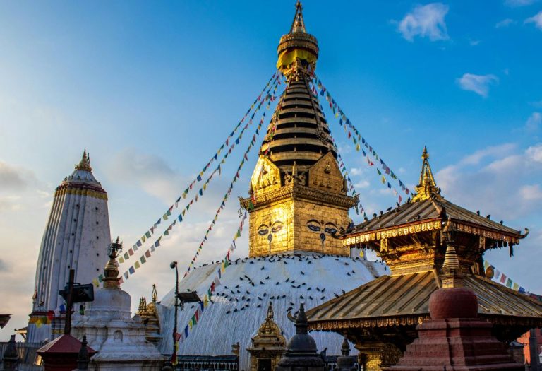 Boeddhistische stupa van Swayambhunath in Kathmandu met kleurrijke gebedsvlaggen en gouden details in het warme avondlicht.